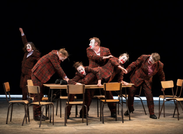 A troupe of hapless clowns sit huddled round a table at HOME Manchester