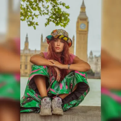 promotional image of Rubberband Girl sat in through of the Thames and Parliament - image courtesy Melody Berkery