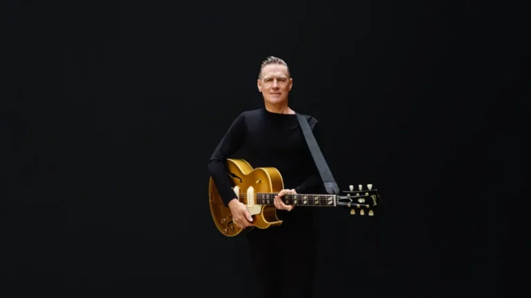 promotional image of Bryan Adams holding a guitar