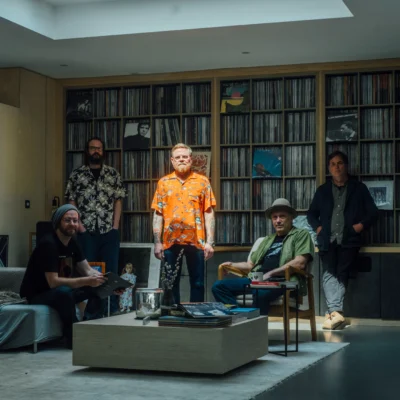 promotional image of Danny & The Champions of the World sat in front of bookshelves - image courtesy Simon Weller