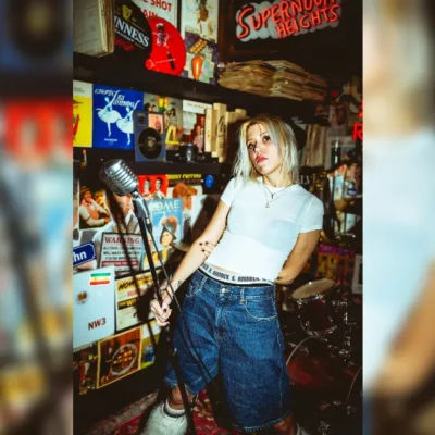 image of Kate Klein stood with a microphone and drum kit