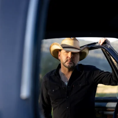 promotional image of Jason Aldean stood next to a trust